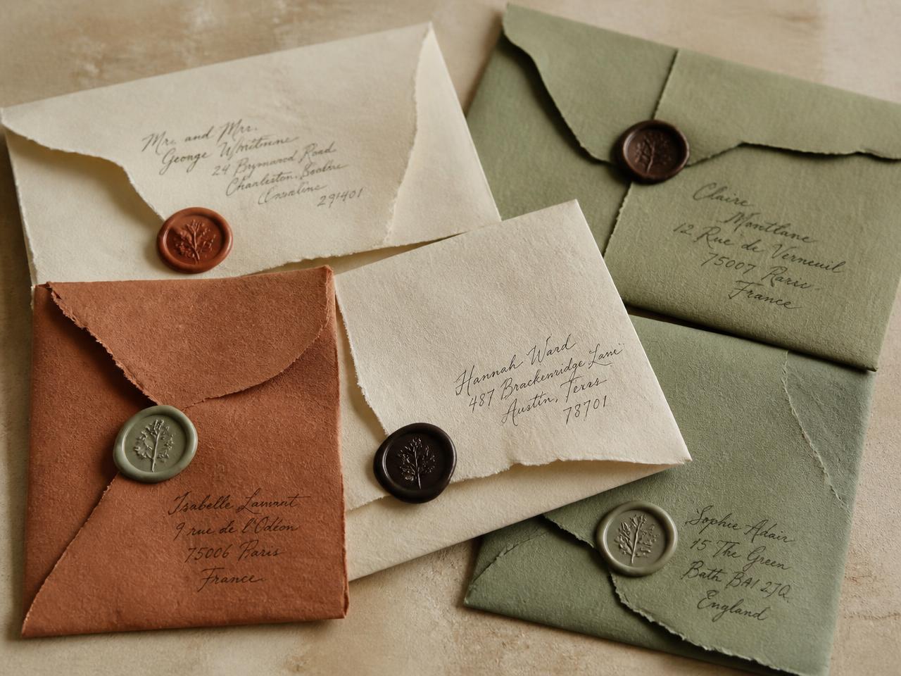 Hand-folded cream, terracotta and sage envelopes with wax seals and calligraphy