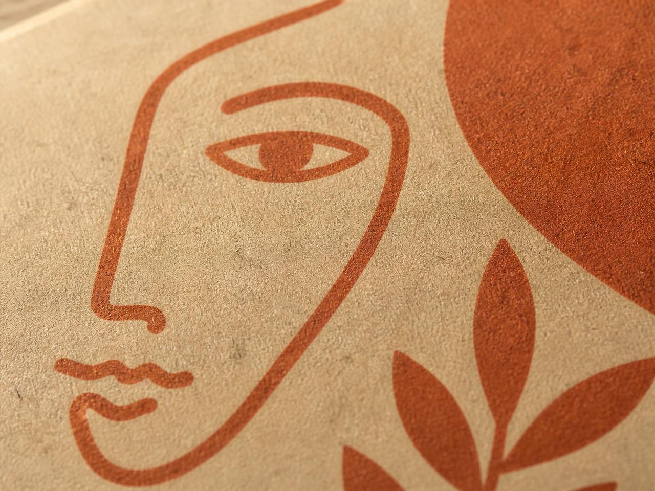 Macro of a line-art face screen printed in terracotta ink on kraft paper