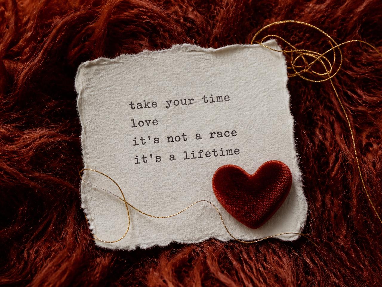 Torn handmade paper card with typewriter text and a velvet heart on terracotta mohair